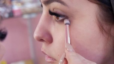 Profesyonel bir makyöz, makyaj stüdyosunda özel bir fırçayla gri göz farı sürer.