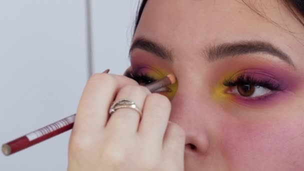 Un maquillador profesional aplica sombra de ojos amarilla con un cepillo especial en un estudio de maquillaje — Vídeos de Stock