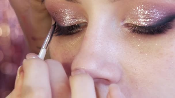 Speciell svart eyeliner penna. Professionell make-up artist gör makeup till en ung vacker flicka i en skönhetsstudio — Stockvideo