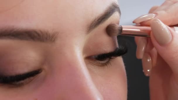 Ένας επαγγελματίας μακιγιέρ εφαρμόζει σκιά ματιών με ένα ειδικό πινέλο σε ένα στούντιο μακιγιάζ — Αρχείο Βίντεο