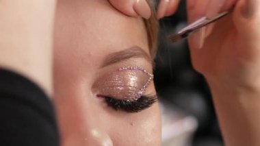 Özel bir fırçayla profesyonel bir makyaj sanatçısı genç ve güzel bir kız modelin kaşlarının şeklini düzeltir ve boyardı. Parlak moda makyajı.