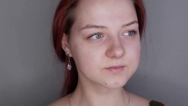 Gyönyörű lány modell pózol a kamera előtt. fiatal nő nélkül smink alkalmazása előtt smink szürke háttér — Stock videók