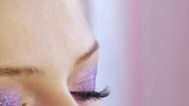 Uzun siyah kirpik uzantıları olan güzel mor göz makyajının yakın görüntüsü.