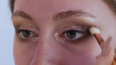 Güzel, parlak gölgeler modelin göz kapağına özel bir fırçayla uygulanır. Parlak akşam makyajı süreci yakın çekim görüntüsü