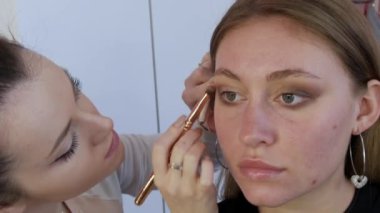 Göz farı, modelin göz kapağına özel bir fırçayla uygulanır. Parlak akşam makyajı süreci yakın çekim görüntüsü