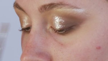Güzel, parlak gölgeler modelin göz kapağına özel bir fırçayla uygulanır. Parlak akşam makyajı süreci yakın çekim görüntüsü