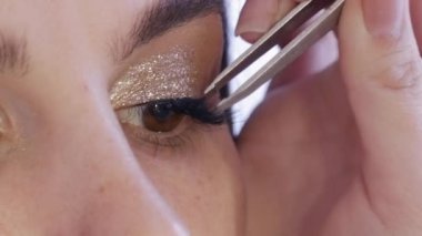 Makyöz, stüdyodaki genç ve güzel kadın modellere takma kirpik yapıştırıyor.