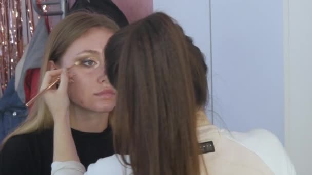 Kamenskoe, Oekraïne - 31 maart 2021: Professionele make-up kunstenaar en stylist werken aan het imago van de modellen waardoor ze make-up — Stockvideo