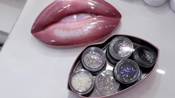 Un conjunto de diferentes diamantes de imitación para el maquillaje en frascos especiales en la mesa en el estilista maquillaje artista — Vídeos de Stock