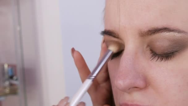 Mooie expressieve ogen van een jong vrouwelijk model met heldere rokerige ogen make-up. Toegewijde make-up borstel brengt glinsterende donkere kameleon oogschaduw — Stockvideo