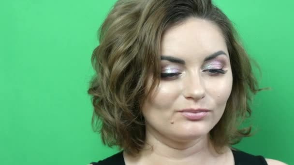 Mladá krásná žena s večerní make-up unavený obličej vypadá vyčítavě. Dívka pózující na zeleném pozadí — Stock video