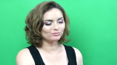 Akşam makyajlı genç ve güzel bir kadın yeşil arka planda cips yiyor.