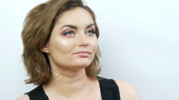 Mladá krásná žena s večerní make-up unavený obličej vypadá vyčítavě a přísně. Dívka pózující na bílém pozadí — Stock video