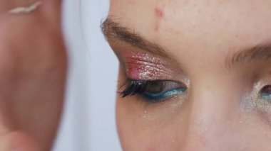 Genç ve güzel bir kız model, profesyonel bir makyaj salonunda parlak bir gece turkuvaz göz makyajına sahte kirpik yapıştırıyor..