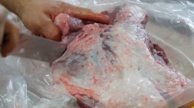 Kanlı ve kanlı büyük bir parça domuz bir erkek kasap tarafından parçalara ayrılır.