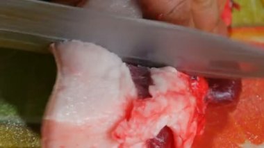 Adam büyük bir parça domuzu bıçakla kesiyor. Domuz yağı, deri ve et parçalara ayrılır..