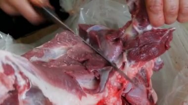 Kanlı ve kanlı büyük bir parça domuz bir erkek kasap tarafından parçalara ayrılır.