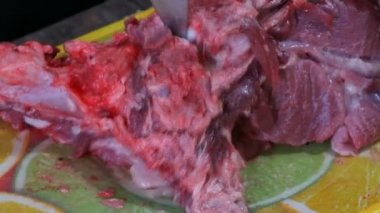 Kanlı ve kanlı büyük bir parça domuz bir erkek kasap tarafından parçalara ayrılır.