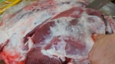 Erkek kasap büyük bir parça domuz bacağı kesiyor..