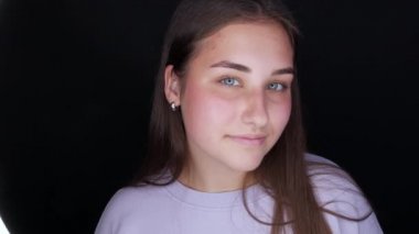 Kameranın önünde poz veren güzel bir manken. Gri arka plana makyaj yapmadan önce makyajsız genç bir kadın.