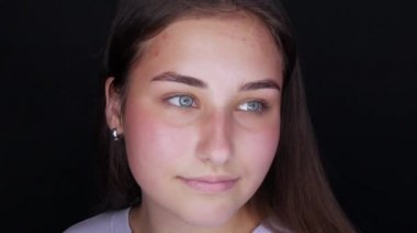 Kameranın önünde poz veren güzel bir manken. Gri arka plana makyaj yapmadan önce makyajsız genç bir kadın.