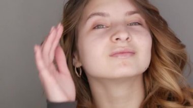 Gri kazaklı kahverengi gözlü güzel bir genç kız kameranın önünde poz veriyor. Doğal güzellikte makyajsız bir model.