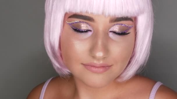 Piękna młoda dziewczyna model pozowanie w różowy krótki Bob peruka, kryształy na jej oczy i stylowy różowy makijaż, wysoka moda. Zbliżenie twarzy — Wideo stockowe