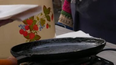 Hamurun gelecekteki krepler için kızartıldığı büyük bir gözleme tavası. Maslenitsa bayramı, Slavlar arasında bahar toplantısının hayati bir kutlaması, bir sokak yemeği festivali. Bir adam bir krep alır