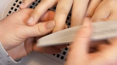 Manikürcü tırnakların şeklini özel bir tırnak törpüsüyle dosyalar. Özel manikür araçları ev görüntüsünde tırnakları parlatır