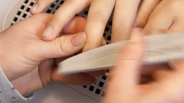 The manicurist files the shape of the nails with a special nail file. Special manicure tools polish on nails at home close up view — Stock Video