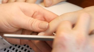 Manikürcü tırnakların şeklini özel bir tırnak törpüsüyle dosyalar. Özel manikür araçları ev görüntüsünde tırnakları parlatır