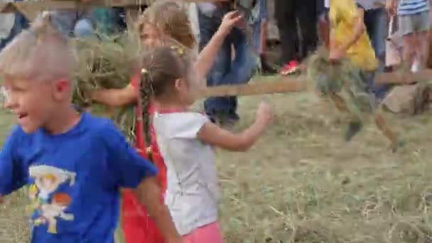 Trostyanets, Ucrânia - 21 de agosto de 2021: Engraçado crianças alegres felizes brincando com feno no festival, jogando feno uns contra os outros, se divertindo e rindo — Vídeo de Stock