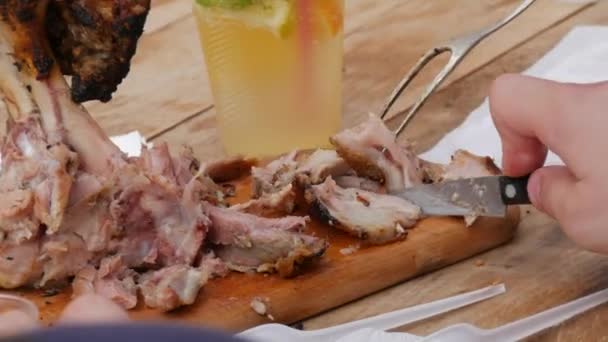 Mužská ruka řízne nožem velkou, tlustou, šťavnatou vepřovou kotletu, která byla právě usmažena. Street food festival, venkovní piknik — Stock video