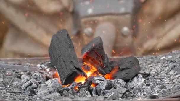 Las pieles de herrero bombean aire para encender fuego en un horno de carbón forjado tradicional. Carbón caliente con chispas de llama listo para oler metal, vista de cerca — Vídeo de stock