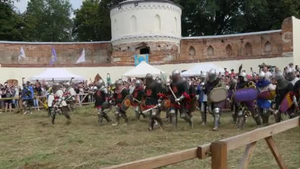 Trostyanets, Ucraina - 21 agosto 2021: Gli spettatori guardano con interesse alla riproduzione della battaglia medievale. Persone vestite con armature cavalleresche e caschi metallici e scudi combattono con acciaio freddo — Video Stock