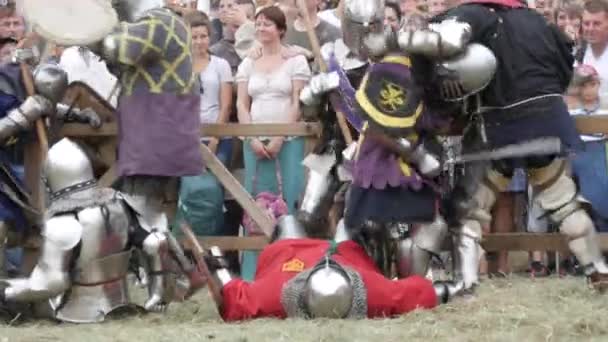 Trostyanets, Ucrania - 21 de agosto de 2021: Los espectadores miran con interés la reproducción de la batalla medieval. Las personas vestidas con armadura de caballero y cascos de metal y escudos luchan con acero frío — Vídeos de Stock