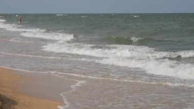 Ukrayna 'nın Azov Denizi kıyısında köpüklü güçlü dalgalar. İnsanlar denizde yüzer.