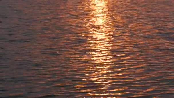 Promienie zachodzącego czerwonego słońca na powierzchni wody — Wideo stockowe