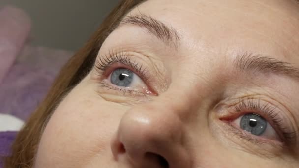 Vuxen kvinna ansikte på modern ögonfrans laminering förfarande i en professionell skönhetssalong efter ögonfrans curling förfarande. — Stockvideo