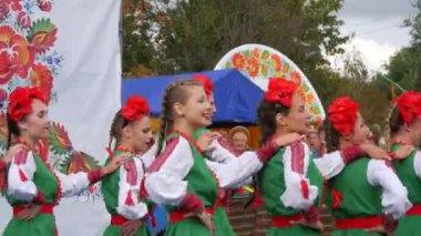 4 Eylül 2021 - Petrykivka, Ukrayna: Ukrayna ulusal kostümlü güzel kızlar ve kırmızı çelenkler festivalde hızlı ve neşeli bir etnik dans