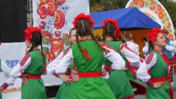 4 de septiembre de 2021 - Petrykivka, Ucrania: Hermosas niñas con trajes nacionales ucranianos y coronas rojas bailan una danza étnica alegre en el festival — Vídeos de Stock