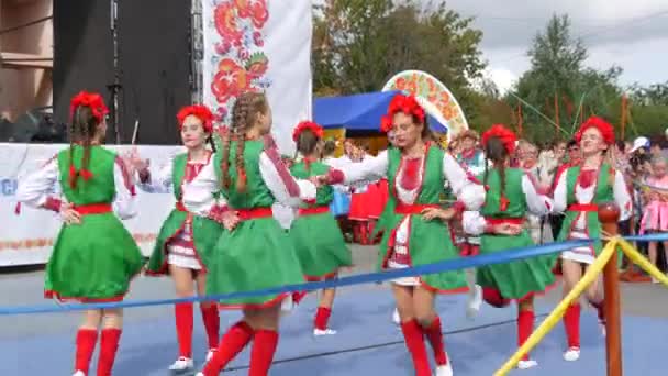 4 сентября 2021 - Петриковка, Украина: Красивые молодые девушки в украинских национальных костюмах и красных венках танцуют на фестивале быстрый веселый этнический танец — стоковое видео
