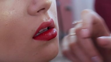 Parlak dudak makyajı, büyük güzel dudaklar bir güzellik salonunda özel bir fırçayla kırmızı rujla boyanır. Profesyonel makyaj malzemesi. Siyah okla Makyaj