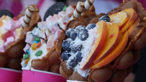 Słodkie gofry z Hongkongu z piankami, czekoladą, cukierkami z jagodami i jagodami oraz marmoladą na blacie sklepu ze słodyczami — Wideo stockowe