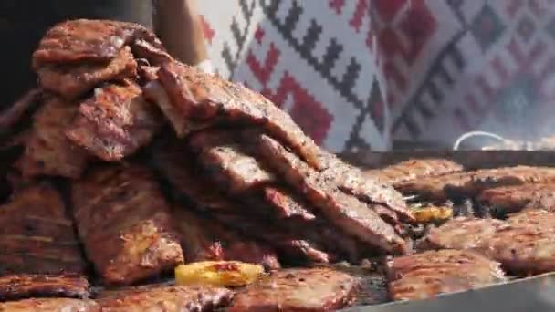 Pečená vepřová žebírka se grilují na velkém grilu z černého uhlí. Festival pouličního jídla. Smažené, nezdravé jídlo — Stock video