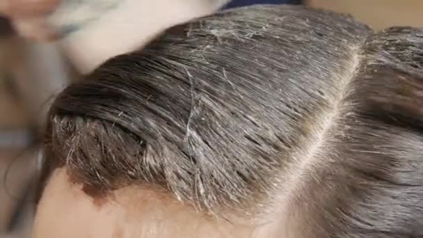 Tintura di capelli femminili in un colore scuro in un salone di parrucchiere. parrucchiere mano applicato pigmento colorante nella pelle del salone di bellezza cliente vista da vicino — Video Stock