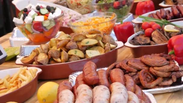 Rijkelijk gedekte tafel met worsten, gegrilde groenten, paprika, courgette, aubergine, aardappelen. Straat voedsel festival, vettig voedsel, fast food — Stockvideo