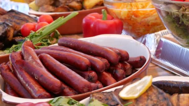 Rijkelijk gedekte tafel met worsten, gegrilde groenten, paprika, courgette, aubergine, aardappelen. Straat voedsel festival, vettig voedsel, fast food — Stockvideo