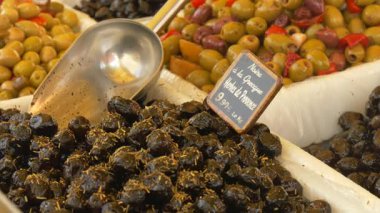 Fransız pazarında güneş ışığında yeşil ve koyu zeytinlerin kırsal görüntüsü. El yazısıyla yazılmış bir Fransız fiyat etiketi otantik Akdeniz atmosferine ekleniyor