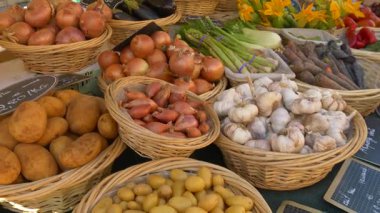 Provence 'de soğan, sarımsak, patates ve diğer yerel sebzelerle dolu sepetlerle dolu bir köy marketi. El yazısı Fransız fiyat etiketleri otantik Akdeniz cazibesine eklenir